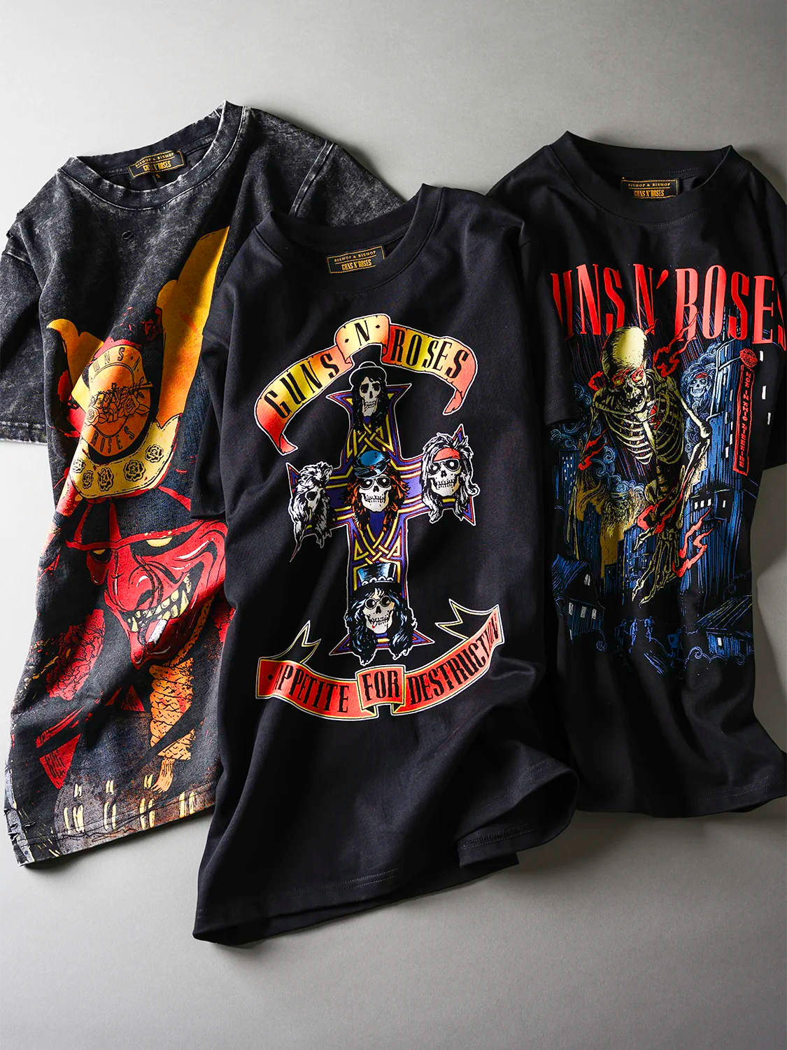 Three Guns N' Roses t-shirts with graphic designs on a gray background